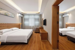 A hotel room with a large bed, a smaller bed, a desk, a chair, and a TV.