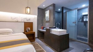 Camera d'albergo con letto, comodino, scrivania, lavandino e doccia.