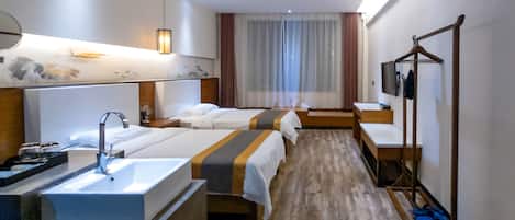 A hotel room with a large bed, a smaller bed, a desk, a vanity with a mirror, and a hanging light fixture.