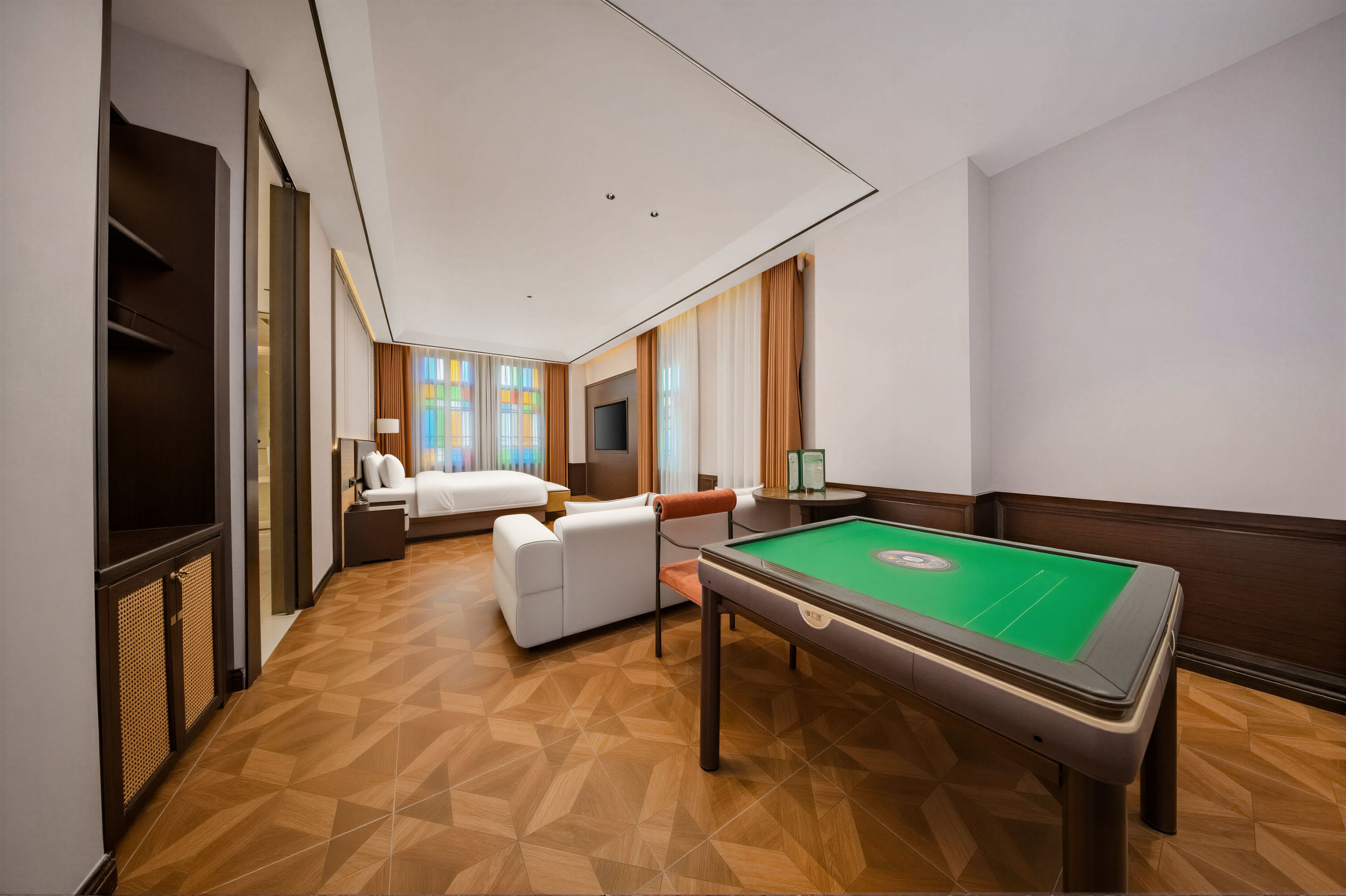 Quarto de hotel com mesa de bilhar, cama, sofá e televisão.