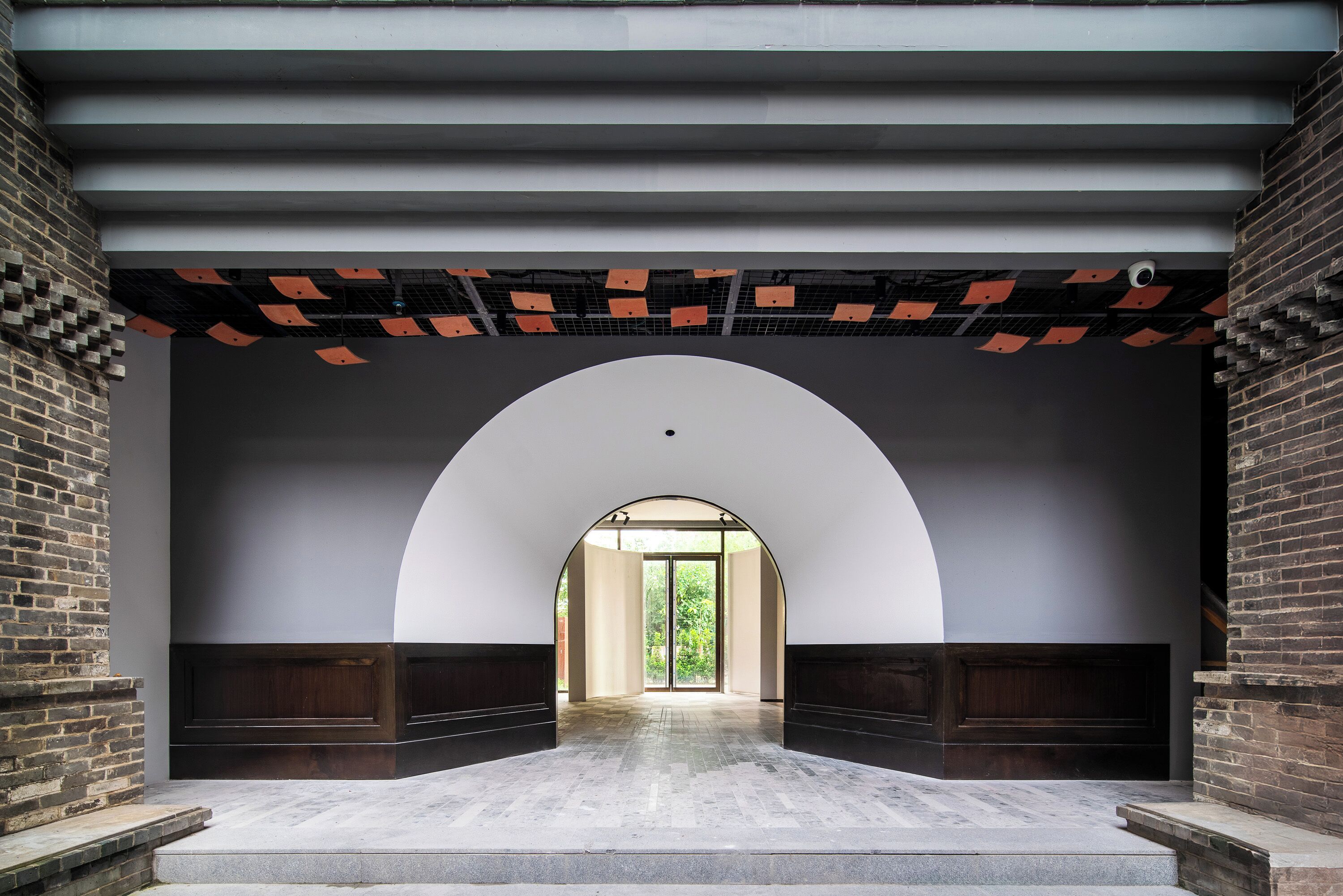 An arched hallway with a view of a green outdoor area.