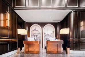 A reception area with two counters, dark wood paneling, and a large mural of a building.