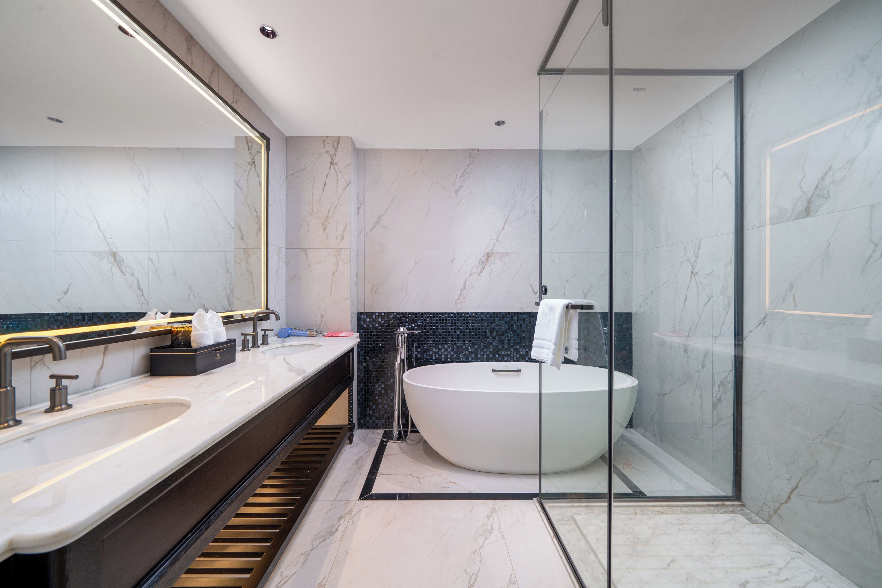A modern bathroom with a large bathtub, a double sink, and a glass shower enclosure.