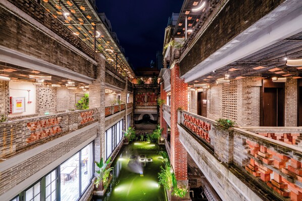 A narrow alleyway with brick buildings, a water feature, and outdoor seating.