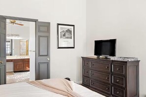 A bedroom with a bed, a dresser with a television, a framed picture on the wall, and an open door leading to a bathroom. - Tempe Coco-Ari 🌵⛳ Heated Pool, Firepit & Space for 9 in South Tempe (Tempe)