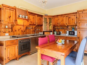 Eine Küche mit Holzschränken, einer Granit-Arbeitsplatte, einem Edelstahlbackofen, einer Mikrowelle und einem Esstisch mit Stühlen.