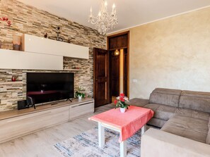 Ein modernes Wohnzimmer mit Flachbildfernseher, Kamin, einer Kristallleuchtre und einem Sofa.