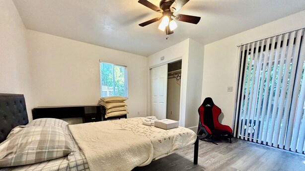 A bedroom with a bed, a desk, a chair, a ceiling fan, and a window with blinds. - Spacious 5BR Pet-Friendly Retreat on a 14,000 Sq Ft Lot (Stockton)