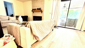 A living room with a sofa, a coffee table, a fireplace, and a sliding glass door to the outside. - Spacious 5BR Pet-Friendly Retreat on a 14,000 Sq Ft Lot (Stockton)