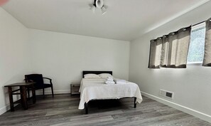 A bedroom with a bed, a chair, a desk, and a window with curtains. - Spacious 5BR Pet-Friendly Retreat on a 14,000 Sq Ft Lot (Stockton)