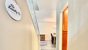 A hallway with a wooden floor, a staircase on the left, and a door on the right. - Spacious 5BR Pet-Friendly Retreat on a 14,000 Sq Ft Lot (Stockton)
