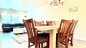 A dining area with a wooden table and chairs, a chandelier, and a sofa in the background. - Spacious 5BR Pet-Friendly Retreat on a 14,000 Sq Ft Lot (Stockton)