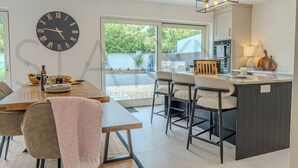 Eine moderne Küche mit einer großen Uhr, einem Essbereich mit Stühlen und einer Bar.