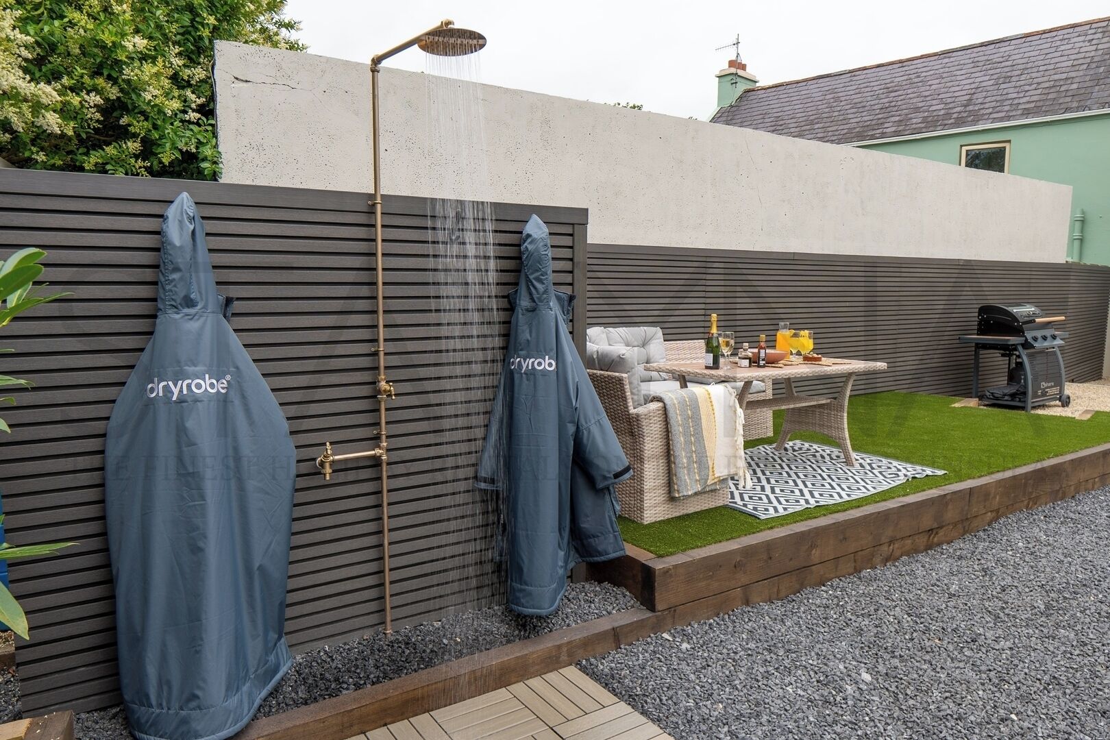 Un espace extérieur aménagé avec un barbecue, une table avec des boissons et un coin salon abrité.