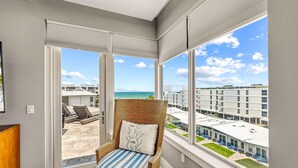 Een balkon met een rieten stoel, uitzicht op het strand en de skyline.