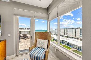 Ein Balkon mit Korbstuhl, Blick auf den Strand und die Stadtlandschaft.