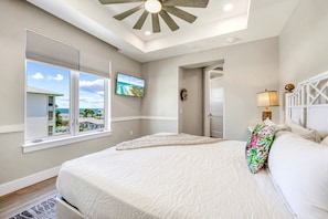 A bedroom with a large bed, a television mounted on the wall, and a view of the ocean through the window. - NEW! Gulf View Suite | Gulf Views, Shared Pool, Exclusive Beach Access (Siesta Key)