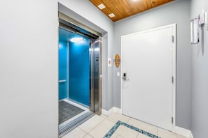 Ein Aufzug mit blauem Innenraum, einer weißen Tür und einer Holzwand.