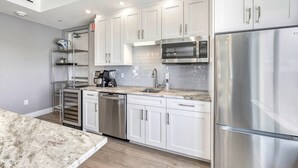 A modern kitchen with stainless steel appliances, white cabinetry, and a marble countertop. - NEW! Gulf View Penthouse | Gulf Views, Hot Tub, Top-Floor Balcony (Sarasota)