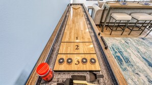 A shuffleboard table with numbered ends, a red drink container, and shuffleboard pucks. - NEW! Gulf View Penthouse | Gulf Views, Hot Tub, Top-Floor Balcony (Sarasota)