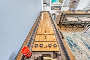 Ein Shuffleboard-Tisch mit nummerierten Enden, ein rotes Getränkegefäß und Shuffleboard-Scheiben.