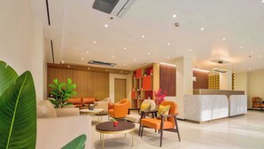 A modern hotel lobby with a reception desk, seating area with sofas and armchairs, and a large plant. - Palette Convention Hotel Millennium City (Gurugram)