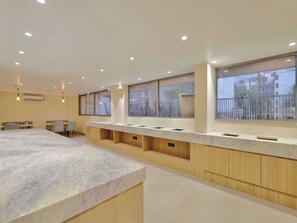 Un moderno vestíbulo de hotel con mostrador de recepción de mármol, paneles de madera y grandes ventanales con vistas al exterior.