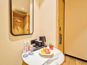 A hotel room with a marble countertop, a coffee maker, a fruit bowl, a potted plant, and a mirror. - Palette Convention Hotel Millennium City (Gurugram)