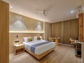 A modern hotel room with a bed, bedside tables, a desk, chairs, a ceiling fan, and a window with curtains. - Palette Convention Hotel Millennium City (Gurugram)