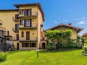 A multi-story building with balconies, a garden, and a clear sky. - Casa Iolanda by Interhome (Carlazzo)
