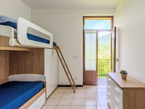 A compact room with a bunk bed, a wooden ladder, a small desk, and a view through a door to an outdoor balcony. - Casa Iolanda by Interhome (Carlazzo)