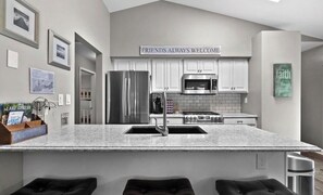 Una cocina moderna con una isla central, electrodomésticos de acero inoxidable y un cartel acogedor sobre los armarios.