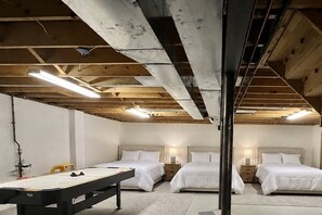 Une chambre avec deux lits, un bureau et une table, dotée de poutres apparentes et d’un éclairage fluorescent.