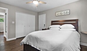 Un dormitorio con cama, ventilador de techo, puerta blanca y un letrero en la pared.