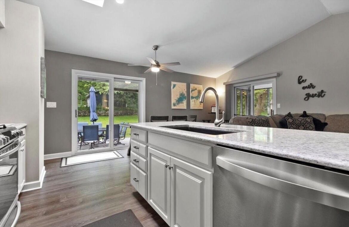 A modern kitchen with a large island, sliding glass doors to a patio, and a ceiling fan.