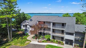 A multi-story building with a balcony, a driveway, and a view of a body of water. - 🏖️ Top-Floor Bay-View 1BR @ The Shores | Grand Traverse Resort | Sleeps 6 (Williamsburg)
