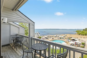 A balcony with a view of a swimming pool and beach.