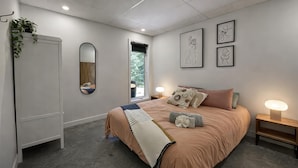 Un dormitorio moderno con cama, mesitas de noche, un espejo y obras de arte en la pared.