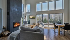 A modern living room with a fireplace, large windows, and a view of the outdoors.