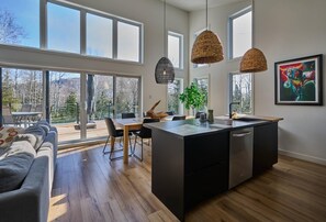 A modern kitchen with a central island, large windows, and a - Éthéra 19: Forest Chalet, Hot Tub & Deck (Petite-Rivière-Saint-François)