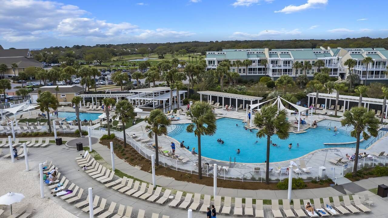 A resort with multiple swimming pools, lounge areas, and a large building in the background.