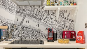A kitchen with a map wall, a coffee machine, a toaster, and various kitchen utensils. - Pet Friendly Studio in Fulham, Sleeps 2 (London)