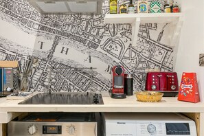 A kitchen with a map wall, a coffee machine, a toaster, and various kitchen utensils. - Pet Friendly Studio in Fulham, Sleeps 2 (London)