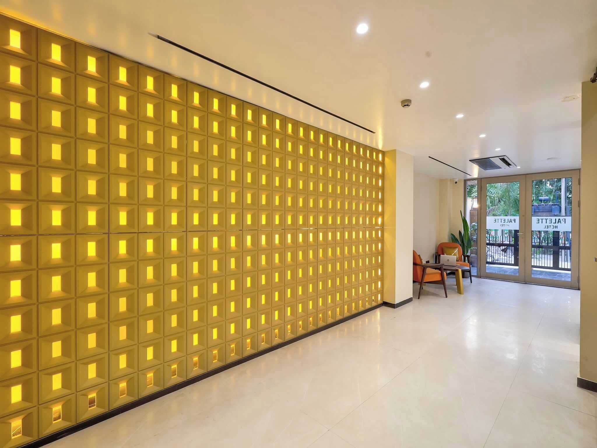Een hotel lobby met een modern wandontwerp, een zithoek met een tafel en stoelen, en een uitzicht door de glazen deuren.
