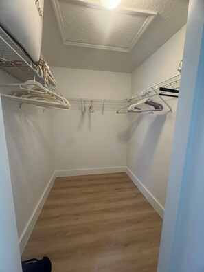 A small, enclosed closet with wooden flooring and metal hangers. - House on the golf course (Ocala)