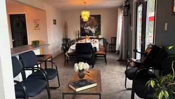 Comedor con una mesa dispuesta para cuatro personas, rodeada de sillas, una araña y un cuadro grande en la pared.