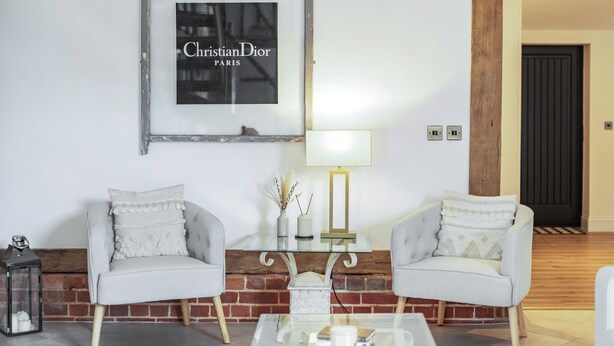 A living room with two grey armchairs, a glass coffee table, a lamp, and a framed picture on the wall. - Barn - Sleeps 10 - Hot Tub - Parking (Reigate)