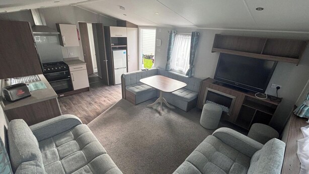 Un espacio habitable compacto con kitchenette, una zona de estar con mesa y televisor.