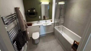 Kylpyhuone, jossa on wc, pesuallas, peili, suihku ja pyyheteline.