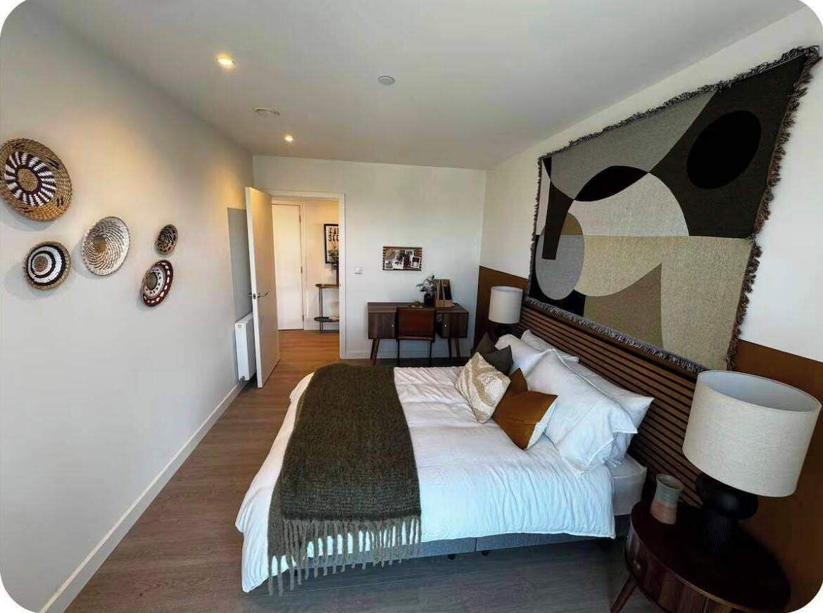 A hotel room with a bed, bedside table, lamp, and wall decor.